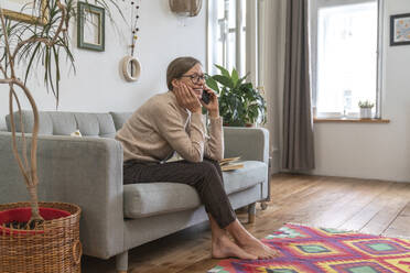 Glückliche Frau, die zu Hause mit ihrem Handy telefoniert - VPIF08079