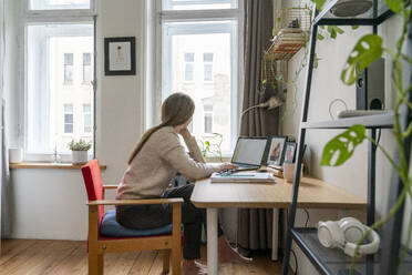 Thoughtful freelancer sitting at desk with laptop - VPIF08089