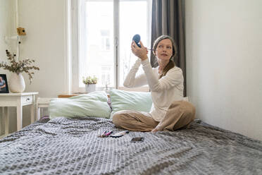 Reife Frau trägt im Schlafzimmer zu Hause Make-up auf das Gesicht auf - VPIF08108