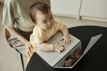 Cute daughter typing on laptop sitting with mother at home - KPEF00006