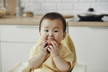 Nettes Mädchen isst Apfel zu Hause sitzend - KPEF00010