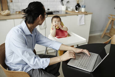 Freelancer father looking at daughter sitting at home - KPEF00014