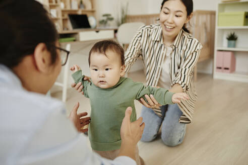 Vater und Mutter unterstützen ihre Tochter bei den ersten Schritten zu Hause - KPEF00049