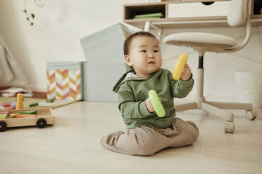 Girl wearing casuals playing with toys sitting on floor at home - KPEF00051