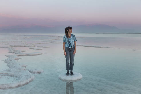 Nachdenkliche junge Frau steht auf einer Salzformation im Toten Meer - PCLF00626