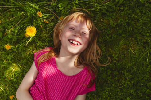 Glückliches erdbeerblondes Mädchen auf Gras liegend - IHF01355