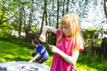 Mädchen hilft Vater beim Vorbereiten des Zeltes für den Campingplatz - IHF01369