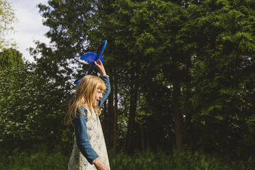 Happy blond girl playing with airplane toy - IHF01377