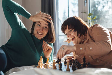 Fröhliches lesbisches Paar spielt zu Hause Schach - JOSEF19480
