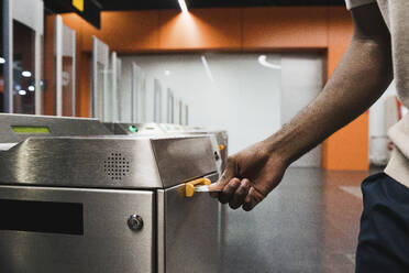 Hand of man inserting metro ticket in electronic barrier - PNAF05301