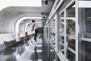 Man wearing futuristic glasses standing at metro station - PNAF05310