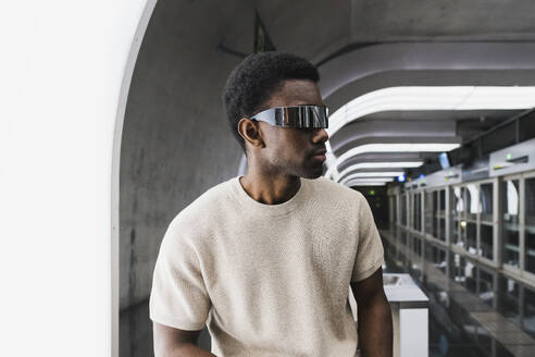 Man wearing futuristic glasses jumping at metro station - PNAF05311