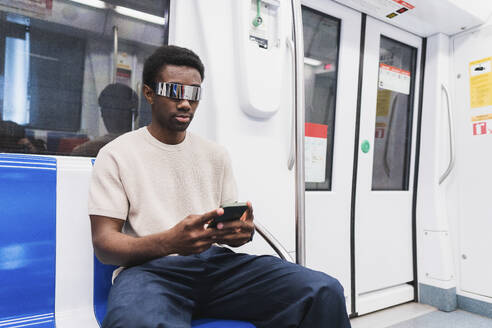 man with cyber glasses using smartphone sitting in metro - PNAF05318