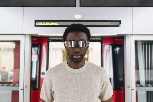 Cyberpunk wearing augmented reality glasses diembarking from metro train - PNAF05322