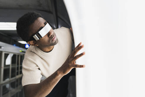 Futuristic man with cyber glasses examining light pane - PNAF05323