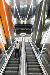 Young man standing on escalator at metro station - PNAF05333