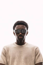 Cool young man wearing cyber glasses against white background - PNAF05337