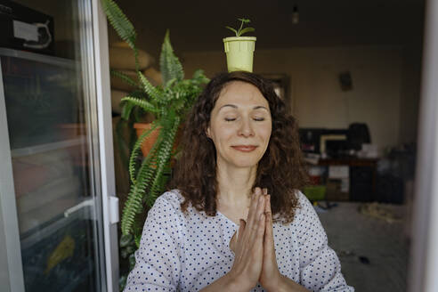 Meditierende Frau mit Topfpflanze auf dem Kopf - IEF00434