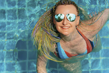 Glückliche Frau genießt und schwimmt im Pool - IEF00442