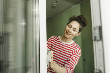 Smiling woman cleaning window frame - IEF00445