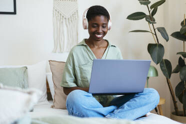 Happy freelancer working on laptop in bedroom - EBSF03419