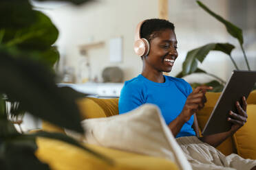 Glücklicher junger Freiberufler mit Tablet-PC auf dem Sofa - EBSF03429