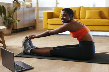 Happy young woman practicing stretching exercise at home - EBSF03438