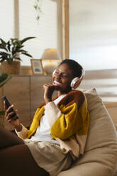 Cheerful woman listening to music and singing at home - EBSF03452