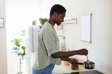 Glückliche junge Frau, die zu Hause Essen kocht - EBSF03472