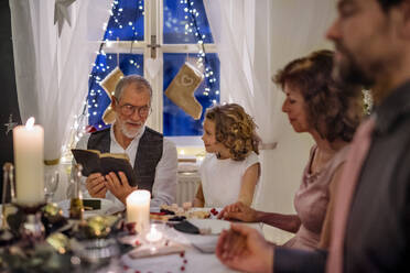 Fröhlicher älterer Mann mit Großfamilie im Haus, der Weihnachten feiert und in der Bibel liest. - HPIF18744