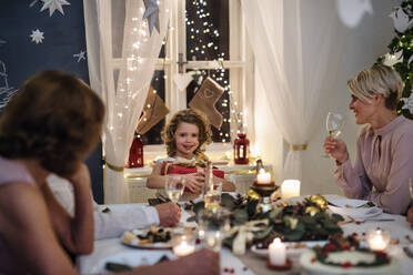 Eine Mehrgenerationenfamilie in einem Haus, die gemeinsam Weihnachten feiert und am Tisch sitzt. - HPIF18747