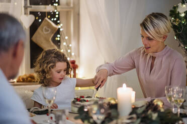 Eine Mehrgenerationen-Familie im Haus, die gemeinsam Weihnachten feiert und am Tisch Kuchen anschneidet. - HPIF18750