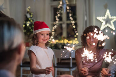 Kleines Mädchen mit Eltern und Großeltern, die drinnen Weihnachten feiern und Wunderkerzen halten. - HPIF18752