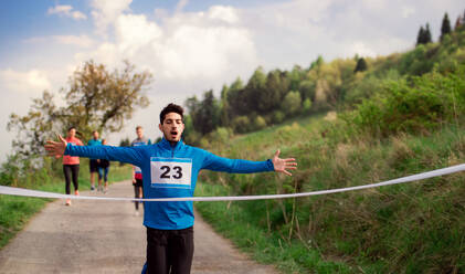 Ein männlicher Läufer beim Überqueren der Ziellinie in einem Wettlauf in der Natur. - HPIF18778