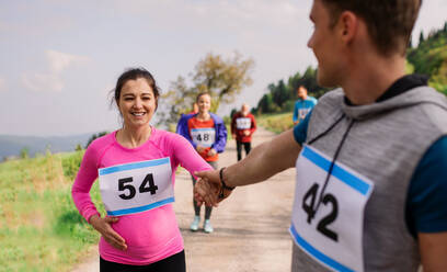 Ein Mann hilft einer schwangeren Frau bei einem Laufwettbewerb in der Natur und geht ihr zur Hand. - HPIF18789