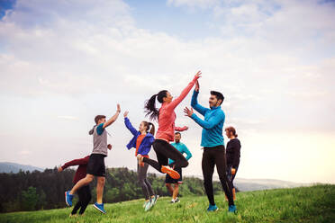 Eine große Gruppe fitter und aktiver Menschen, die nach dem Sport in der Natur springen. - HPIF18822