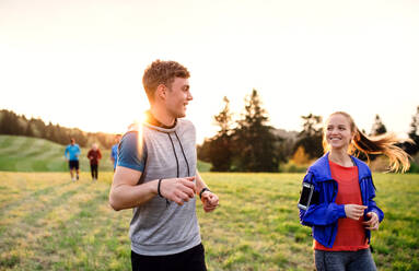 A large group of people cross country running in nature at sunset. - HPIF18858