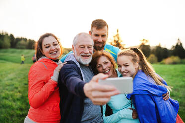 A group of fit and active people resting after doing exercise in nature, taking selfie with smartphone. - HPIF18872