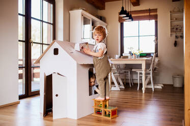 Two toddler children playing with a carton paper house indoors at home. Copy space. - HPIF18920