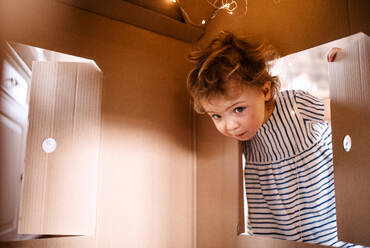 Ein kleines Mädchen spielt zu Hause mit einem Haus aus Papier. Kopierraum. - HPIF18933
