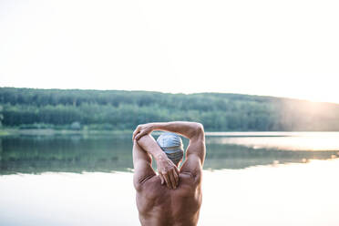 Rückansicht eines älteren Mannes, der vor dem Schwimmen im Freien am See steht und sich streckt; Raum kopieren. - HPIF18959