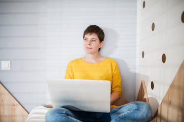 Vorderansicht einer jungen Frau mit Laptop auf dem Bett im Schlafzimmer zu Hause. - HPIF19023