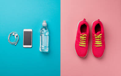 Eine Studioaufnahme von Laufschuhen, Wasserflasche, Kopfhörer und Smartphone auf farbigem Hintergrund. - HPIF19076