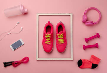 Eine Studioaufnahme von Laufschuhen, Smartphone und andere Sportgeräte auf rosa Hintergrund. flach legen. - HPIF19120