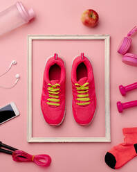 Eine Studioaufnahme von Laufschuhen, Smartphone und andere Sportgeräte auf rosa Hintergrund. flach legen. - HPIF19121