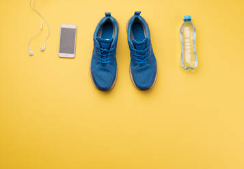 A studio shot of running shoes,water bottle and smartphone on yellow background. Flat lay. - HPIF19128