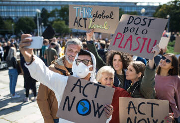 People with placards and protective suit on global strike for climate change, taking selfie. - HPIF19217