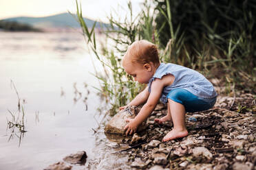 Ein kleines Mädchen im Kleinkindalter, das im Sommer draußen am Fluss spielt. Raum kopieren. - HPIF19233