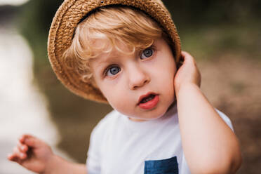 Ein niedlicher kleiner Junge, der im Sommer draußen an einem Fluss steht. - HPIF19262