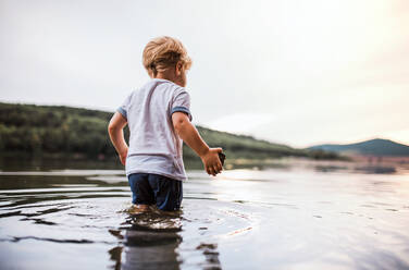 Ein nasses, glückliches Kleinkind, das im Sommer draußen an einem Fluss spazieren geht und spielt. - HPIF19264